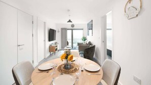 A modern dining area with a round table, chairs, and a vase of flowers. - Bright Apartment Near Shops in Eccles Manchester (Eccles)