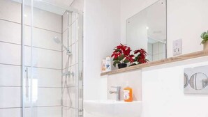 A bathroom with a glass shower enclosure, a white sink, a toilet, and a mirror above the sink. - Bright Apartment Near Shops in Eccles Manchester (Eccles)