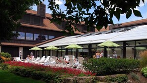 Une terrasse sur le toit, dotée de chaises longues et de parasols, et entourée d’un jardin aménagé.