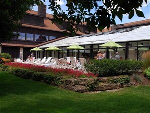 Eine Dachterrasse mit Liegestühlen und Sonnenschirmen, umgeben von einem angelegten Garten.