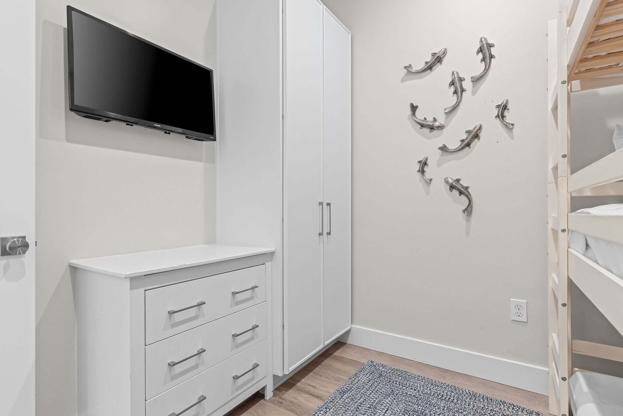 A bedroom with a bed, a wardrobe, a television, and wall art.