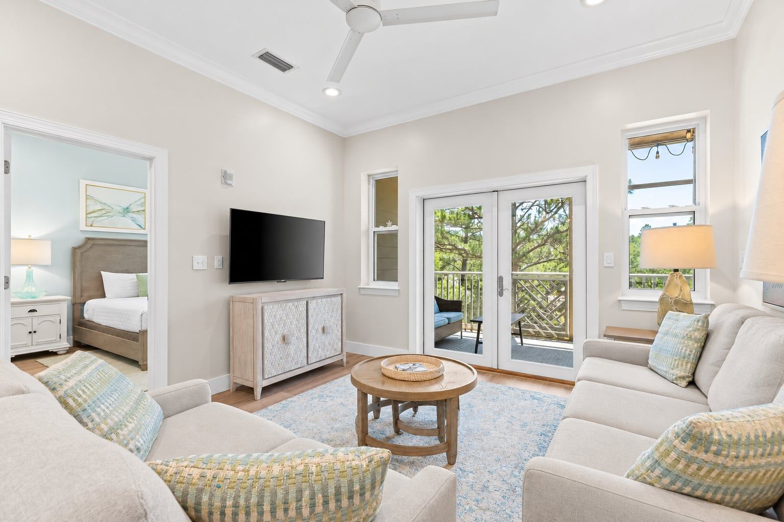 A spacious living room with a flat-screen TV, a sofa set, a coffee table, and a sliding glass door leading to an outdoor area.