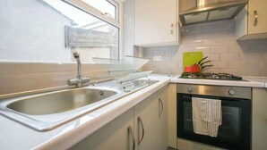 A compact kitchen with a stainless steel sink, a gas stove, and a small oven. - Stylish Modern Getaway : Lancashire (Lancashire)