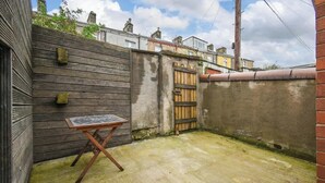 A narrow outdoor space with a wooden table, a metal gate, and a concrete floor. - Stylish Modern Getaway : Lancashire (Lancashire)