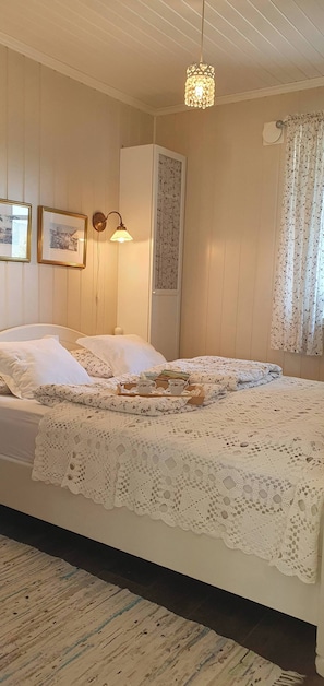 A bedroom with a bed, a nightstand, a lamp, a wardrobe, and a window with curtains. - Serene Fjord View Holiday House in Davik, Nordfjord (Bremanger)