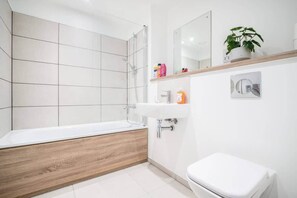 Een moderne badkamer met een badkuip, een wastafel en een toilet.
