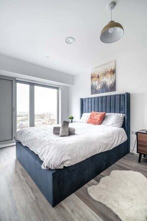 A modern bedroom with a large bed, a view through the window, and a ceiling light. - Elegant Stay at Church Street Place Eccles Area (Eccles)