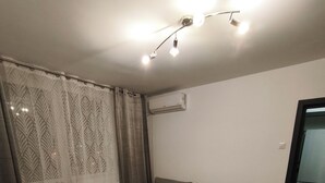 Een woonkamer met een bank, een salontafel, een tv-meubel en een gordijn met een patroon.