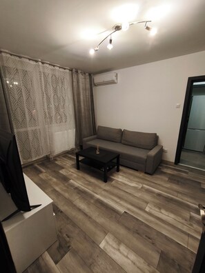 A living room with a sofa, a coffee table, a TV stand, and a patterned curtain. - Apartment F2 (living room + one bedroom) approx. 45m (București)