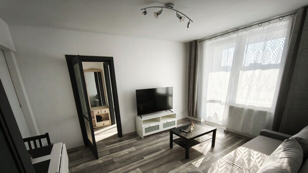Een moderne woonkamer met een bank, een salontafel, een televisie en een houten vloer.