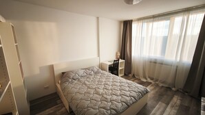 Een slaapkamer met een bed, een bureau en een stoel.