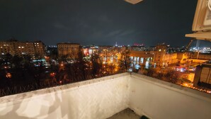 Een balkon met uitzicht op een stadsbeeld bij nacht, met gebouwen en straatverlichting.