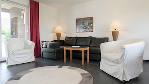 Een woonkamer met een bank, twee fauteuils, een salontafel en twee vloerlampen.
