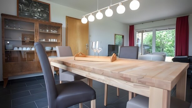 Een eetgedeelte met een houten tafel, stoelen en een wijnglashouder.