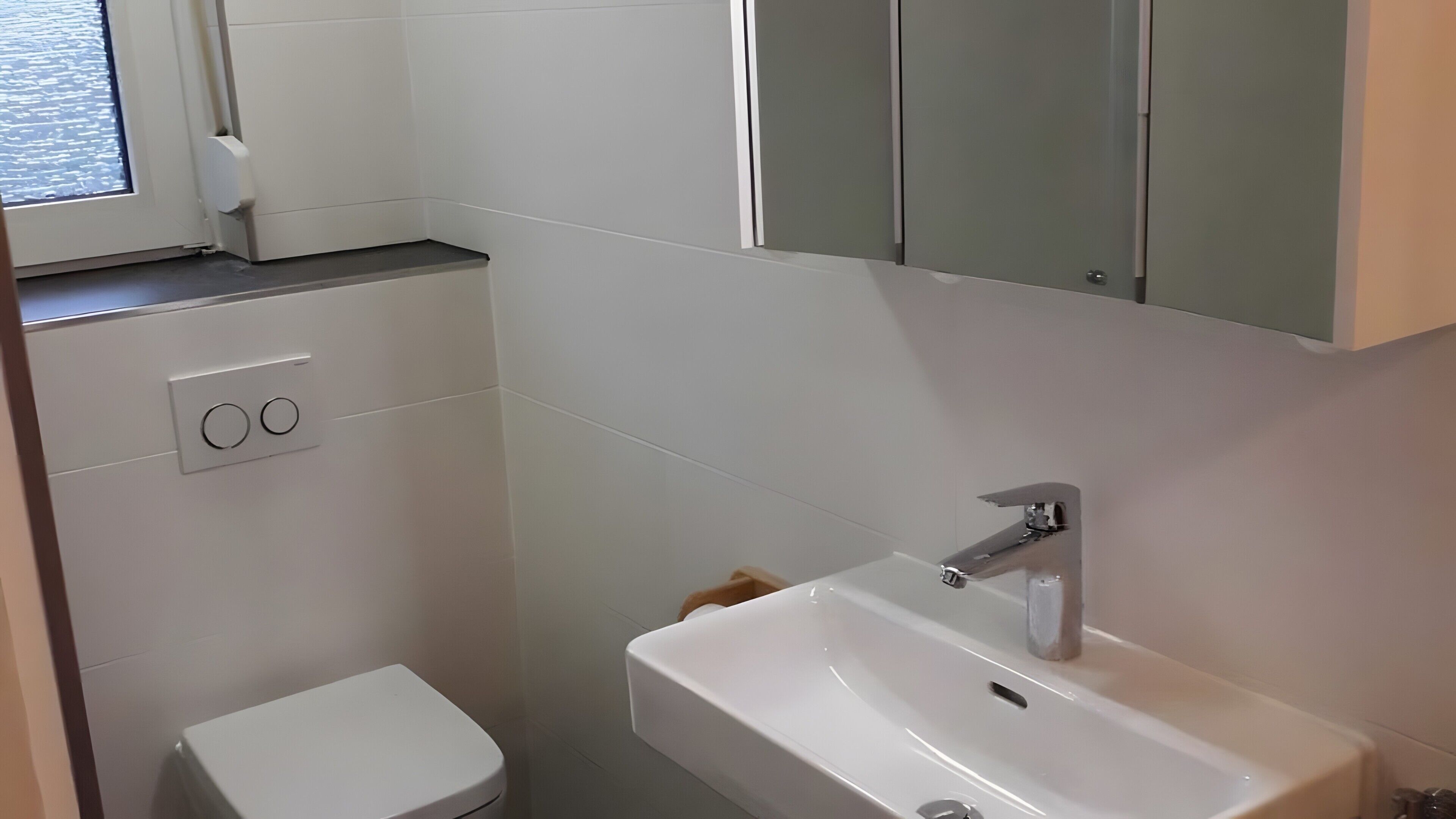 Un baño con inodoro, lavamanos y espejo sobre el lavamanos.