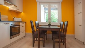 Een keuken met een eettafel, stoelen, een raam en een inbouwoven.