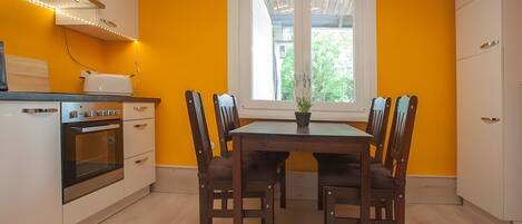 A kitchen with a dining table, chairs, a window, and a built-in oven.