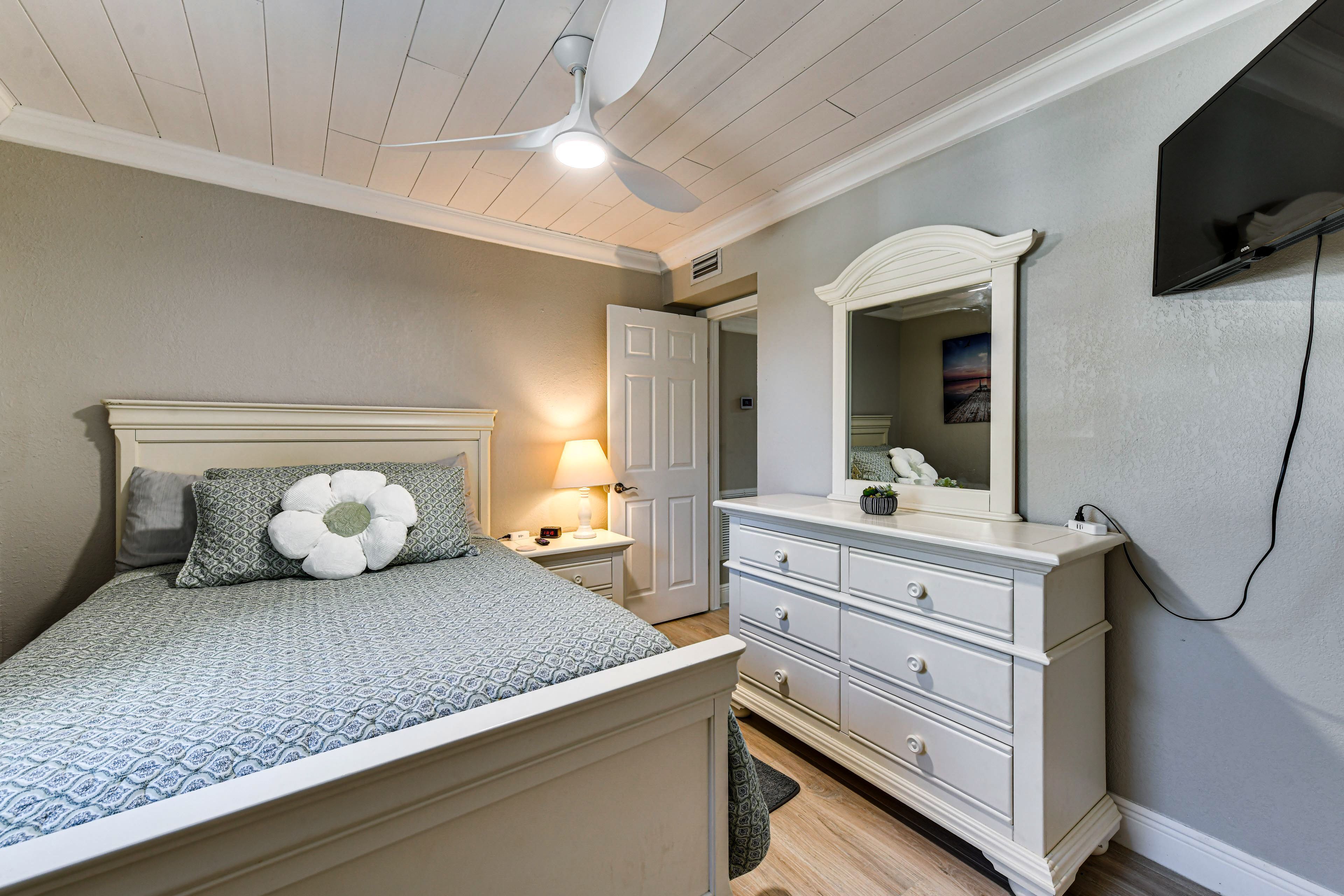 A bedroom with a bed, nightstand, dresser, and a ceiling fan.