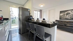 Una cocina moderna con refrigerador, máquina de café y taburetes de bar.