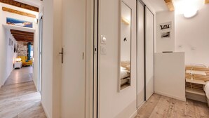 Ett modernt hotellrum med ett träpanelat tak, en säng med en trägavel, en garderob och en spegel.