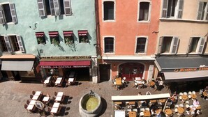En gatubild med uteservering, en fontän och byggnader med skyltar för en restaurang och en pizzeria.
