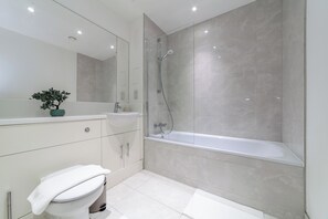 Ein modernes Badezimmer mit Badewanne, Waschbecken, Toilette und Spiegel.