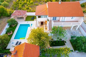 A two-story house with a swimming pool, a patio with outdoor furniture, and a garden. - Holiday Home Dinko with pool (Pridraga)
