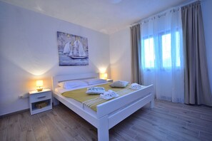 A bedroom with a bed, nightstands, a painting, and a window with curtains. - Holiday Home Dinko with pool (Pridraga)