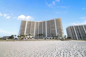 A beachfront hotel with multiple floors, balconies, and palm trees. - Admiral's Quarters 906 by Liquid Life (Orange Beach)
