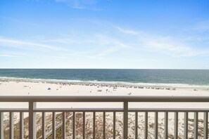A beach view from a balcony with a railing, sandy beach, ocean, and clear sky. - Admiral's Quarters 906 by Liquid Life (Orange Beach)