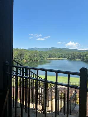 Un balcon donnant sur un lac, entouré de verdure et de collines.