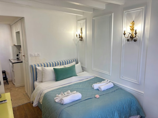 Ein Hotelzimmer mit einem Bett, einer kleinen Küchenzeile und zwei Wandleuchten.