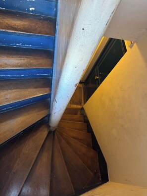 Eine Holztreppe mit weißer Handlauf und einer schwarzen Tür am Fuß.