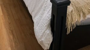 Una cama con ropa de cama blanca, un cabecero de madera oscura y una decoración de cuernos de ciervo montada en la pared.