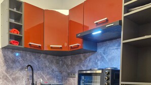 Una cocina moderna con armarios rojos, un microondas negro y un refrigerador negro.