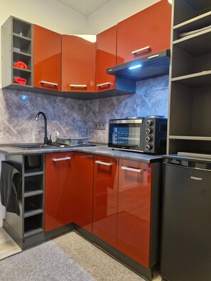 A modern kitchen with red cabinets, a black microwave, and a black refrigerator. - Eselei – Entire Holiday Apartment with Private Entrance (Belm)