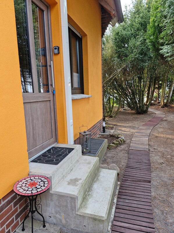 A yellow building with a wooden door, a small outdoor table, and a concrete step leading to the entrance. - Eselei – Entire Holiday Apartment with Private Entrance (Belm)