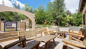 An outdoor seating area with wooden furniture and a signboard. - Holiday Home “Camping Les Pialades - Gîte Spa” with Private Terrace and Wi-Fi (Nabirat)