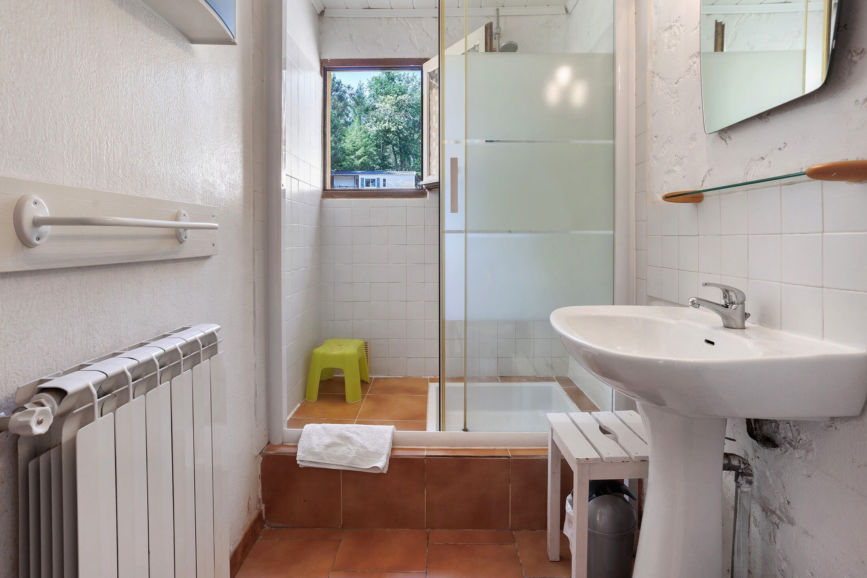 A bathroom with a bathtub, a sink, a window, and a toilet.