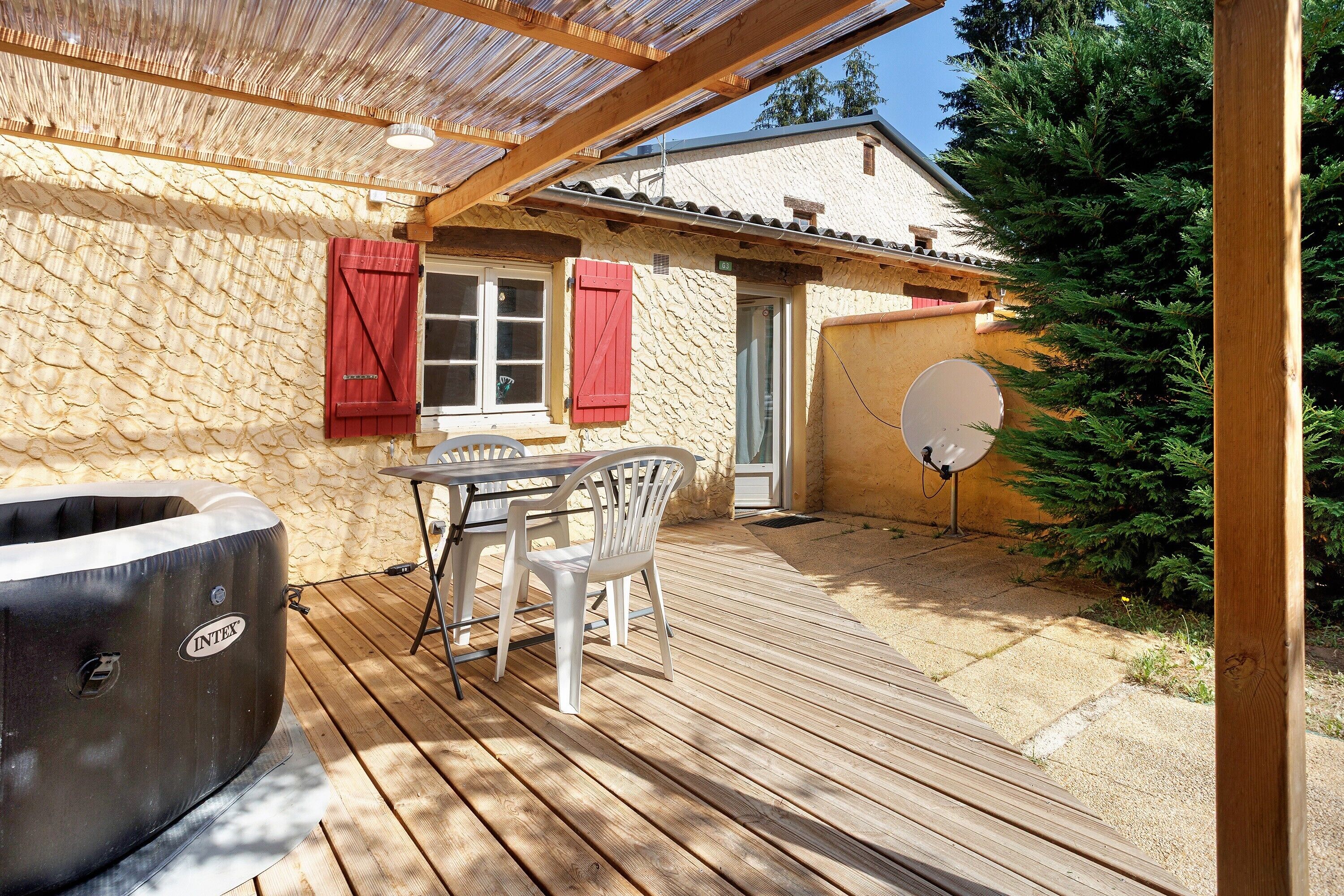 A covered outdoor patio with a hot tub, a table, and chairs.