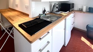 Eine moderne Küche mit weißen Schränken, einer Holzauskładung, einem eingebauten Kochfeld, einer Spüle und einer Mikrowelle.