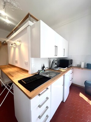 Eine moderne Küche mit weißen Schränken, einer Holzauskładung, einem eingebauten Kochfeld, einer Spüle und einer Mikrowelle.