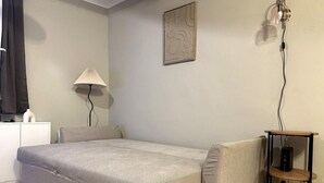 A bedroom with a bed, a bedside table, a lamp, and a wall art piece. - Comfortable apartment in the heart of the city (Toulon)