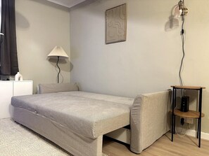 Ein Schlafzimmer mit einem Bett, einem Nachttisch, einer Lampe und einem Wandbild.