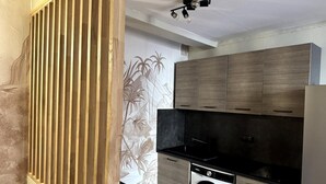 A compact kitchen with wooden cabinets, a black countertop, and a built-in washing machine. - Comfortable apartment in the heart of the city (Toulon)