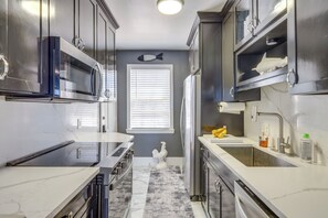 A modern kitchen with stainless steel appliances, a marble countertop, and a decorative rooster statue. - Poolside Fun! Waterfront Gem Near San Marco Square (Jacksonville)