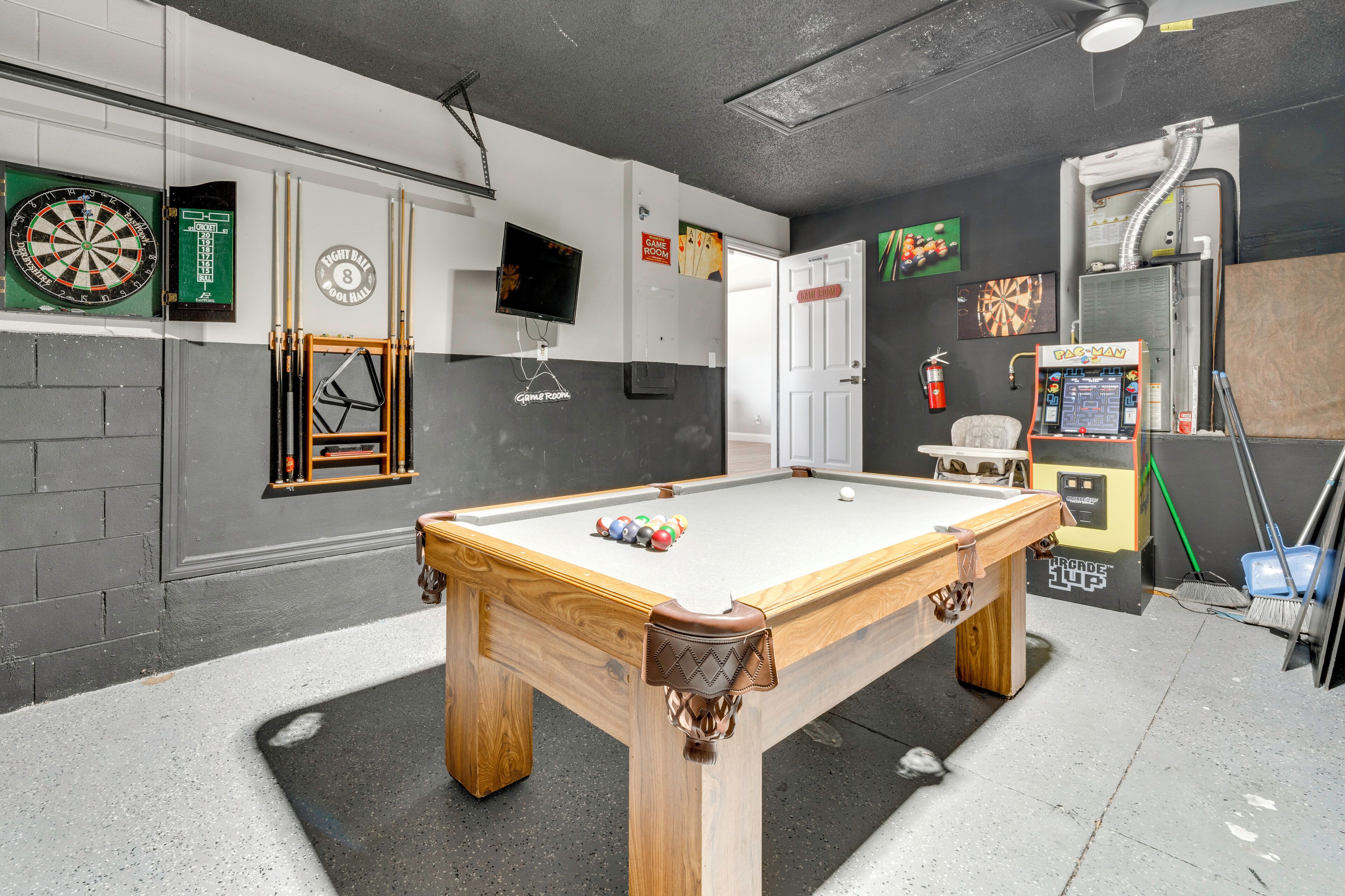 Een pooltafel met ballen, een dartbord, een televisie en een bord met daarop 'Game Room'.