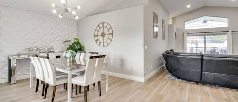 Une cuisine moderne avec une table à manger, des chaises et une horloge au mur.