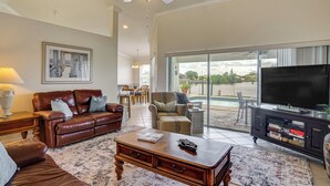 A spacious living room with a leather sofa, a coffee table, and a television on a stand. - Spectacular Views! Largest Canal in NW Cape Coral (Cape Coral)