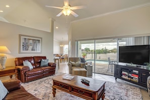 A spacious living room with a leather sofa, a coffee table, and a television on a stand. - Spectacular Views! Largest Canal in NW Cape Coral (Cape Coral)